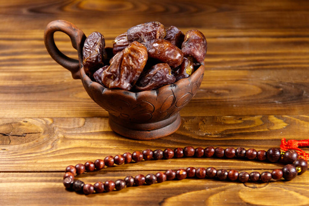 Fechas fruta y rosario en mesa de madera. La fiesta musulmana del mes sagrado del Ramadán - Foto, Imagen
