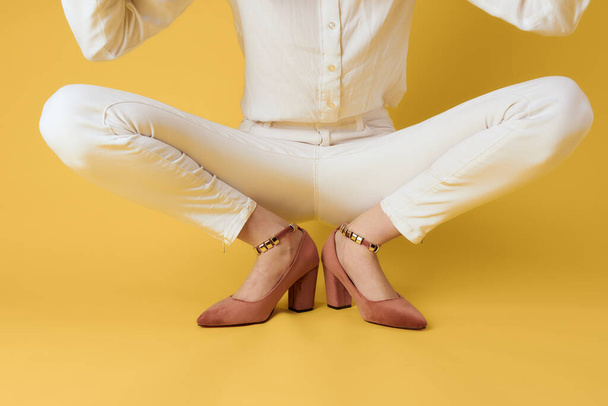 Female legs white pants fashionable clothes shoes luxury yellow background - Fotografie, Obrázek