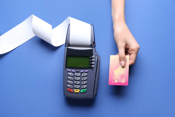 Mano femminile con carta di credito e terminale di pagamento su sfondo a colori - Foto, immagini