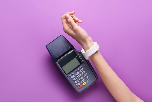 Female hand with smart watch and payment terminal on color background - Photo, Image