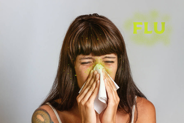 Constipações e doenças virais sazonais. Uma mulher morena espirra ou assoa o nariz em um lenço. Texto FLU e micróbios verdes. - Foto, Imagem