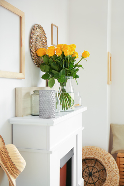 Βάζο με όμορφα κίτρινα τριαντάφυλλα στο τζάκι στο εσωτερικό του δωματίου - Φωτογραφία, εικόνα