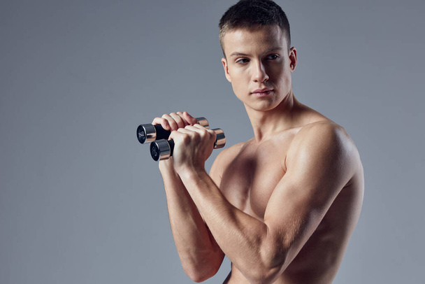 sporty man with pumped body with dumbbells in hands workout fitness cropped view - Photo, image