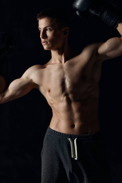 guy with a pumped-up torso gesturing with his hands on a black background boxing gloves  - Foto, Imagen