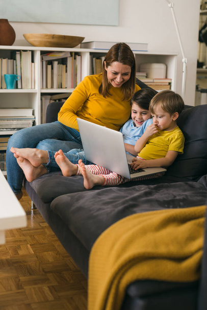 mother and her children using laptop computer while sitting on sofa at homemother and her children using laptop computer while sitting on sofa at home - Φωτογραφία, εικόνα