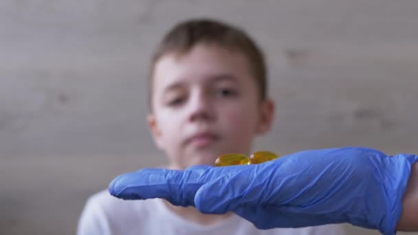 Doutor, um pediatra que usa luvas de nitrilo de látex, dá à criança dois comprimidos. 4K - Filmagem, Vídeo