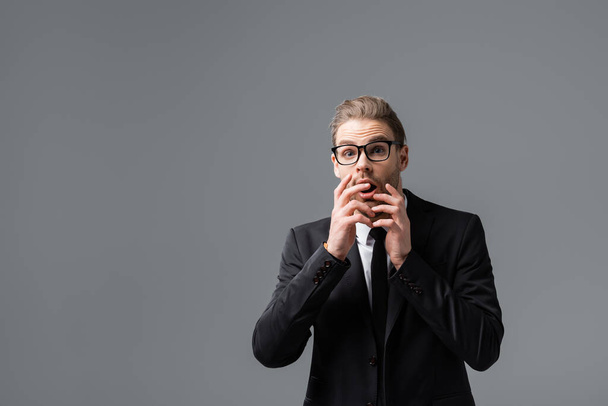 afraid businessman covering mouth with hands while looking at camera isolated on grey - Photo, Image