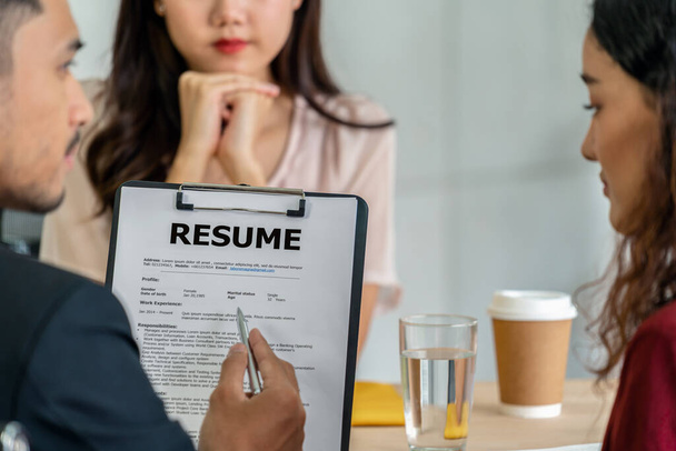 Closeup Resume in two manager hand holding when discuss about her resume with serious motion over Young Asian woman graduate interviewing in meeting room,Business Hiring new member concept - Photo, Image