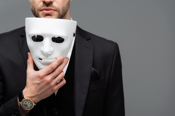 καλλιεργημένη άποψη του επιχειρηματία που κρατά μάσκα προσώπου απομονωμένη σε γκρι - Φωτογραφία, εικόνα
