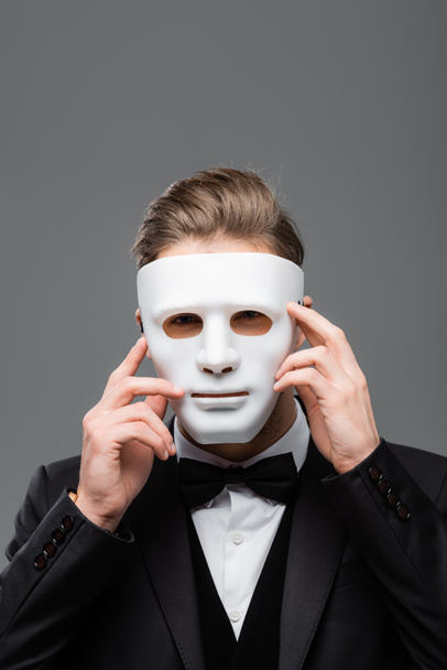 jeune homme d'affaires cachant visage avec masque isolé sur gris - Photo, image