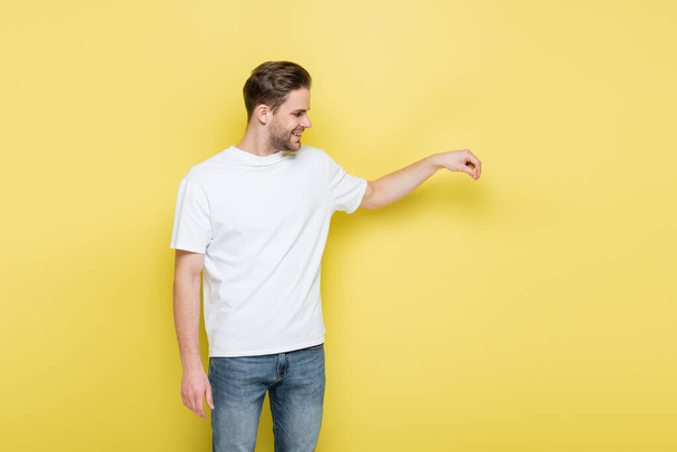 mosolygós férfi fehér pólóban, kezében valami sárga - Fotó, kép