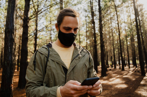 Male alone in the woods during covid19 pandemic texting on cell phone - Foto, immagini