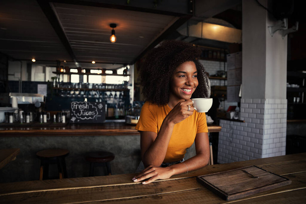 Mixed race female customer enjoying hot coffee sitting in rustic restaurant  - Zdjęcie, obraz