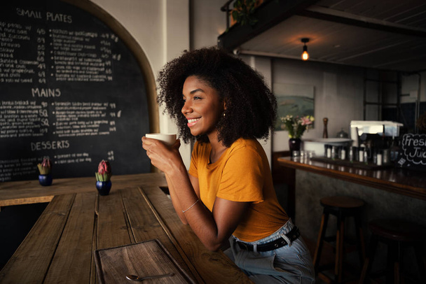 Smiling customer relaxing while enjoying hot coffee in trenedy cafe  - Zdjęcie, obraz