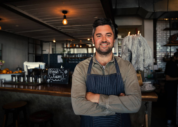 Bello maschio cameriere sorridente in piedi con le braccia incrociate in caffè alla moda  - Foto, immagini