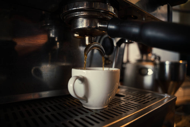Close-up van koffiezetapparaat produceren espressos voor klanten in funky cafe  - Foto, afbeelding