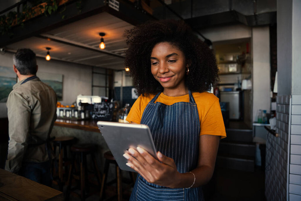Smiling waitress choosing meal option for customer scrolling on digital tablet in trendy cafe  - Foto, Imagem