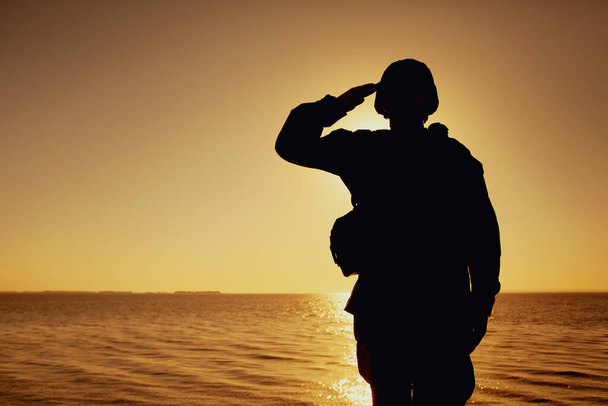 Silhouette of soldier salutes on sunset background - Photo, Image