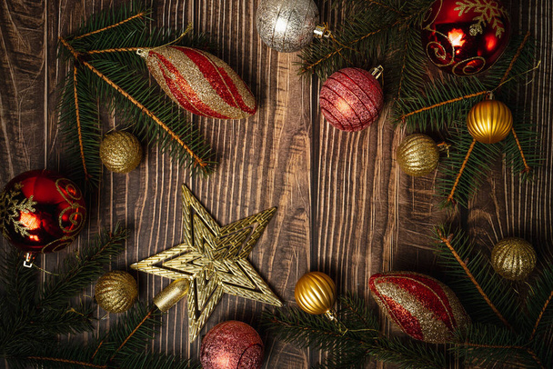 New Year's decor on a wooden background. Fir branches, Christmas balls and wooden toys. Cozy home. Place for the text. View from above - Photo, Image
