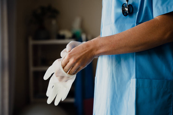 Primer plano de la doctora en matorrales poniendo guantes de cirujano en las manos - Foto, imagen