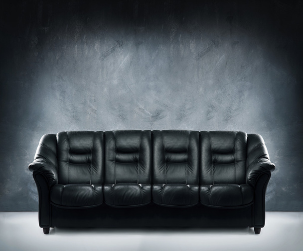 Black leather sofa in dramatic interior - Foto, afbeelding