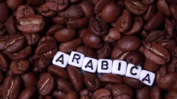 deslizándose a través de granos de café tostados con palabra ARABICA escrito en pequeños cubos blancos. Arabica, Robusta - Metraje, vídeo