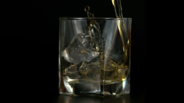Zeitlupe des Einfüllens von Whiskey in Glas mit Eis, dunkler Hintergrund  - Filmmaterial, Video