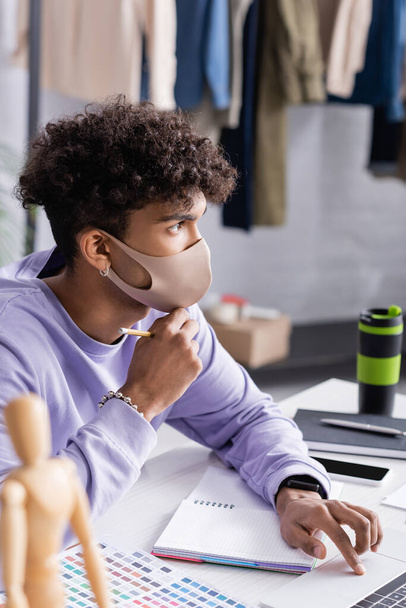 Afrikkalainen amerikkalainen liikemies suojaava naamio kannettavan tietokoneen lähellä kannettavan showroom  - Valokuva, kuva