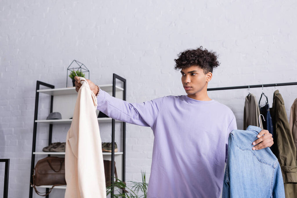 Propriétaire afro-américain de showroom tenant des chemises sur cintres  - Photo, image