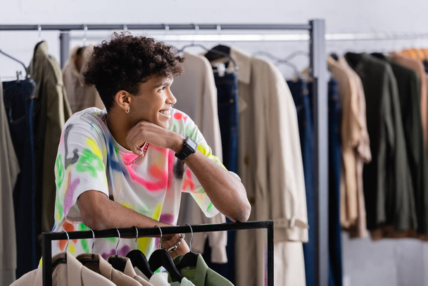 Стильный афроамериканец владелец магазина одежды, стоящий рядом с вешалкой  - Фото, изображение