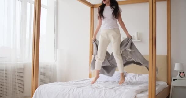 Excited woman jumping on her bed  - Footage, Video