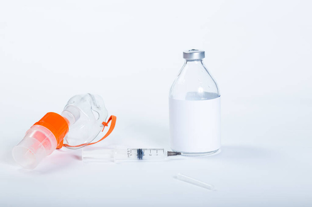 Máscara de nebulizador com seringa e frasco médico de vidro em um fundo branco. - Foto, Imagem