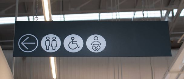 Знак у ванну зліва чорно-білий символ вішається, щоб побачити. Знак містить символи зі стрілками ліворуч, жінки, чоловіки, інваліди та діти. Вибірковий фокус. Розмитий фон
 - Фото, зображення
