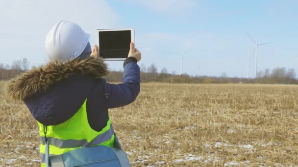 Female engineer with digital tablet take pictures of turbine farm - Footage, Video