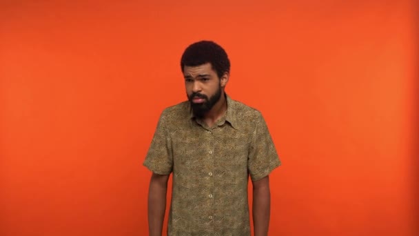 ontevreden Afro-Amerikaanse man toont schouders en geen gebaren geïsoleerd op oranje - Video