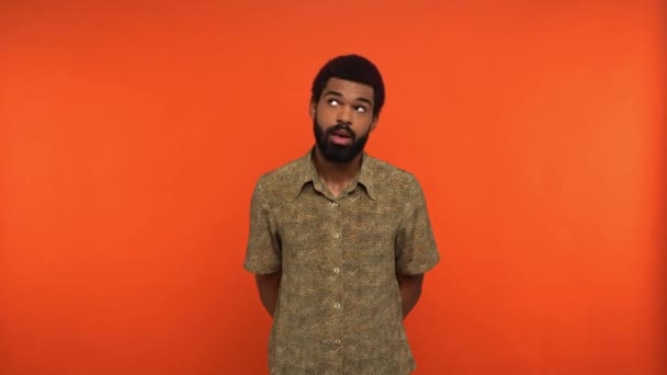 töprengő afro-amerikai férfi néz körül, és beszél elszigetelt narancs - Felvétel, videó