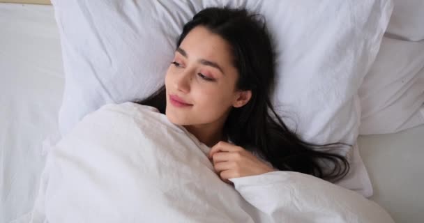 Boldog nő felébred és pihen az ágyon a hálószobában - Felvétel, videó