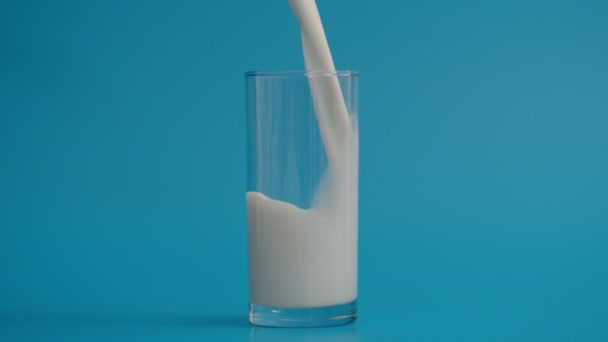 Zeitlupe des Einfüllens von Milch in Glas bei 1000fps, blauer Hintergrund  - Filmmaterial, Video