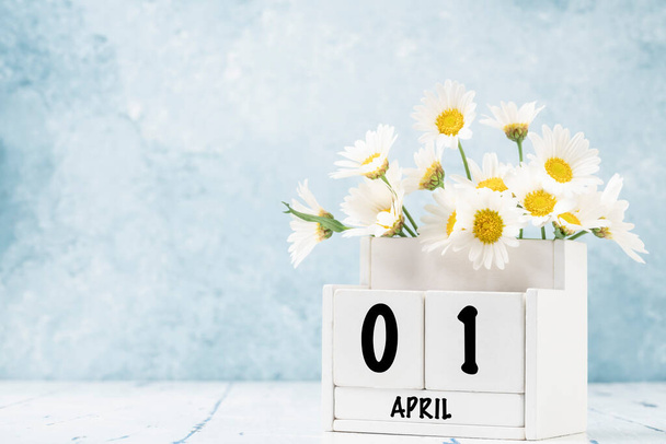 Calendário cubo branco para abril decorado com flores de margarida sobre fundo azul com espaço de cópia - Foto, Imagem