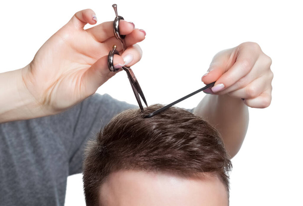 Un parrucchiere fa un taglio di capelli per un giovane in un barbiere. - Foto, immagini