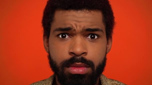 cámara lenta de hombre afroamericano enojado aislado en naranja - Imágenes, Vídeo