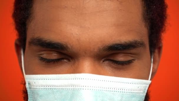 slow-motion van Afro-Amerikaanse man met medisch masker geïsoleerd op oranje - Video