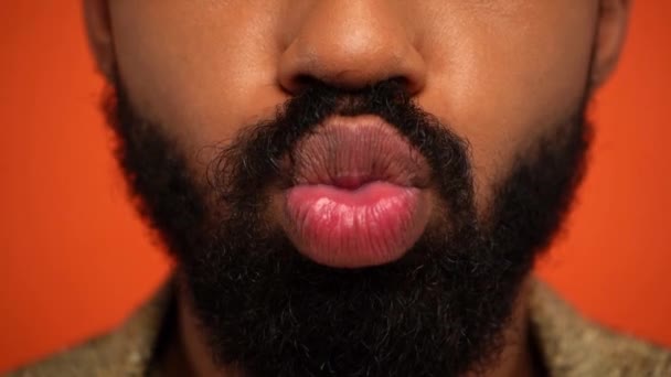 μερική άποψη του γενειοφόρου της Αφρικής Αμερικανός άνθρωπος pouting χείλη απομονώνονται σε πορτοκαλί - Πλάνα, βίντεο