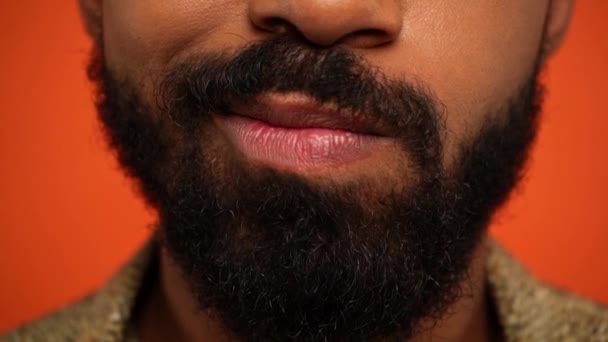 részleges kilátás szakállas afro-amerikai férfi grimaszolás elszigetelt narancs - Felvétel, videó