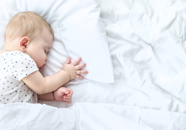 A baba fehér ágyon alszik. Szelektív fókusz. Gyerek. - Fotó, kép