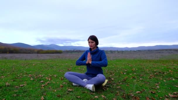 Žena si užívá jógu v podzimním parku poblíž osamělého dubu. cvičení meditace zenu v přírodě. myšlenka a koncept fitness, zdravý životní styl, - Záběry, video