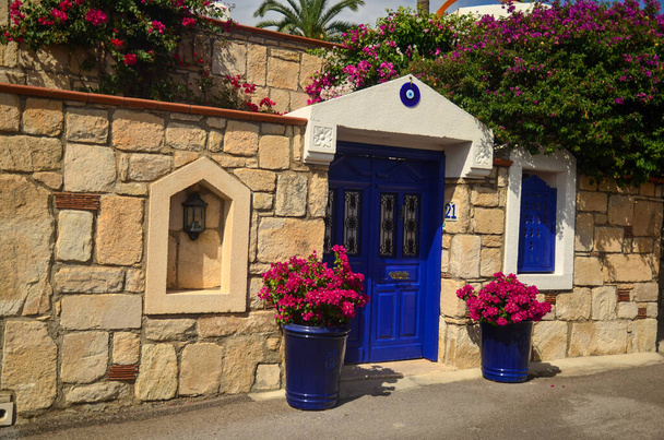 Edificio antiguo de piedra (casa) con puerta y ventanas vintage de madera azul. Hermosas flores rosadas delante. Bodrum tradicional estilo de arquitectura del Egeo  - Foto, Imagen