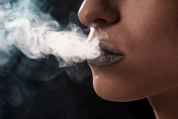 Mulher fumando cigarro em um fundo preto - Foto, Imagem