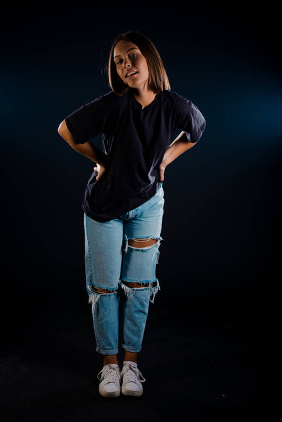 Studio body shot van een trendy jonge vrouw in moderne geripte broek - Foto, afbeelding