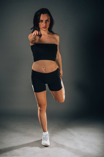 Urheileva nuori nainen joogaharjoituksissa eristettynä pimeälle taustalle. Käsitys terveestä elämästä ja luonnollisesta tasapainosta. Täyspitkä - Valokuva, kuva